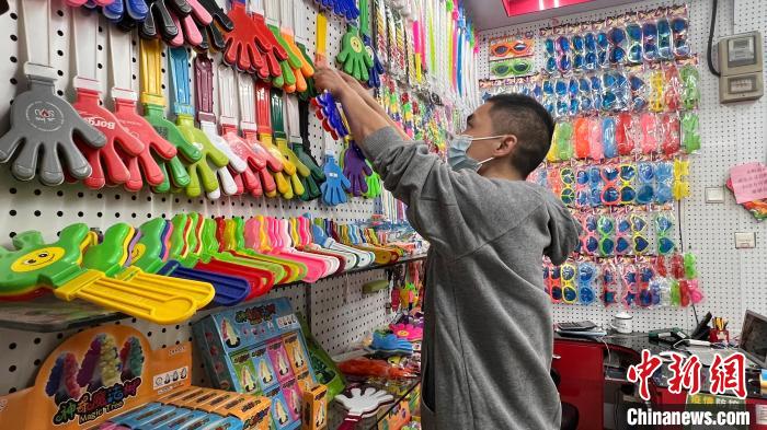 义乌国际商贸城一区,售卖玩具、助威道具等产品的店主潘祥明整理店铺的各色手拍器产品。 董易鑫摄